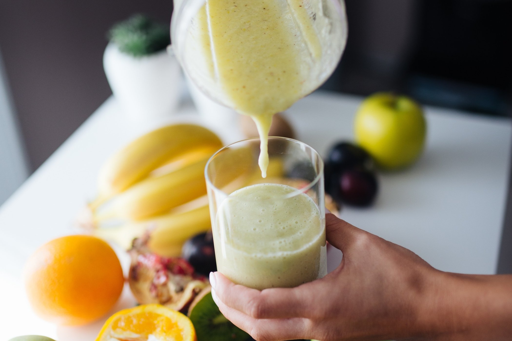 Generic fruit smoothie being poured into a glass with fresh fruit, no visible brand logos