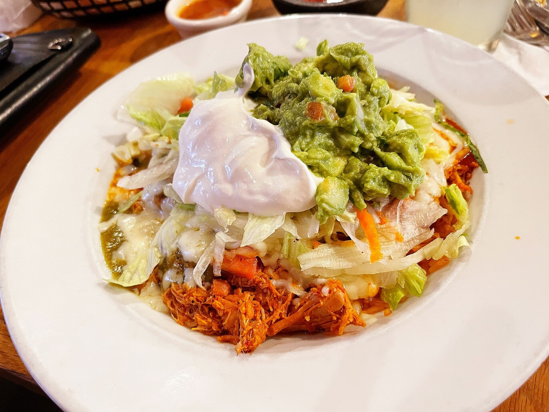 Taco bowl with seasoned meat, lettuce, guacamole, and sour cream