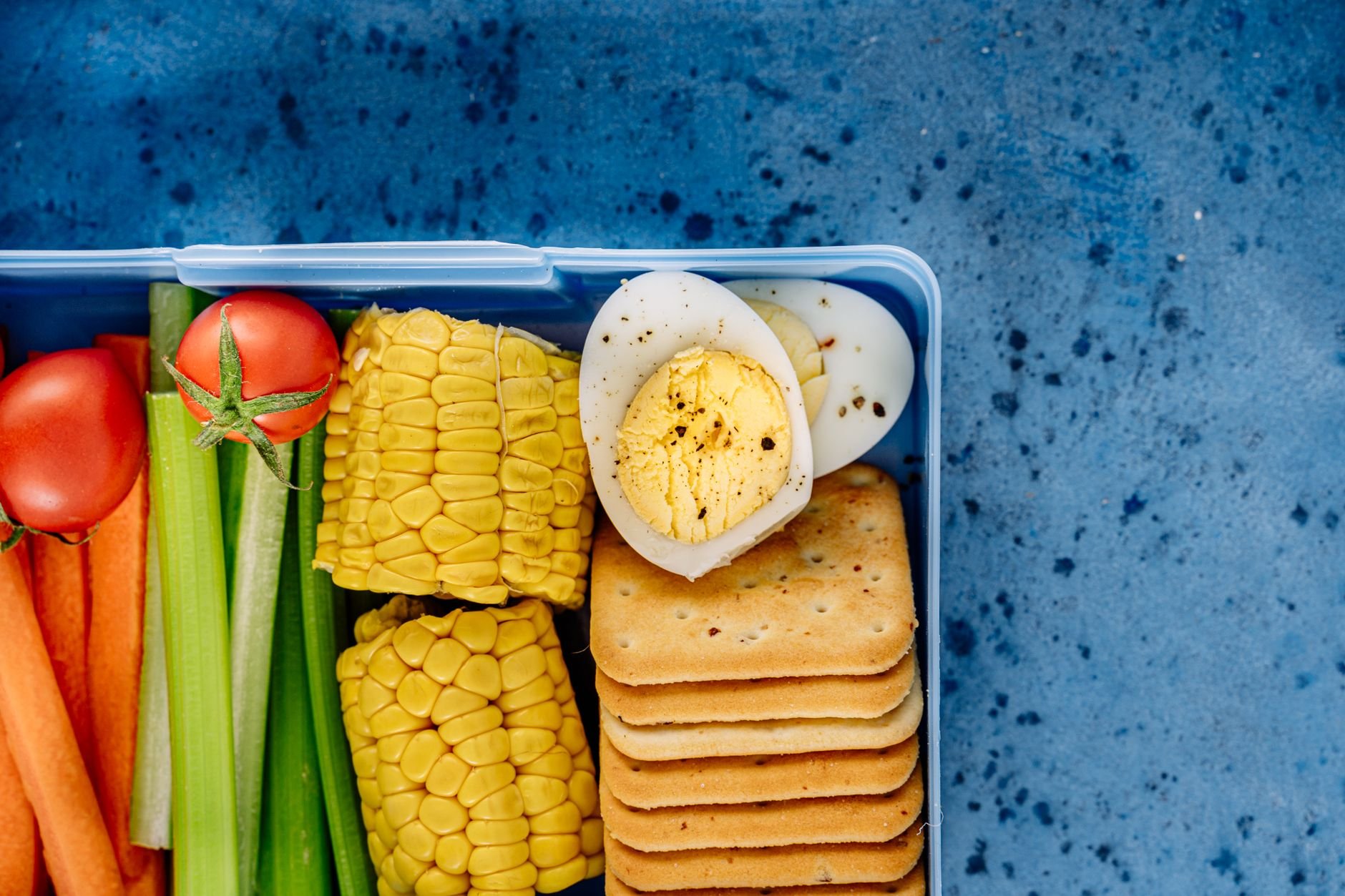Kids lunchbox with boiled eggs, vegetables, corn, and crackers