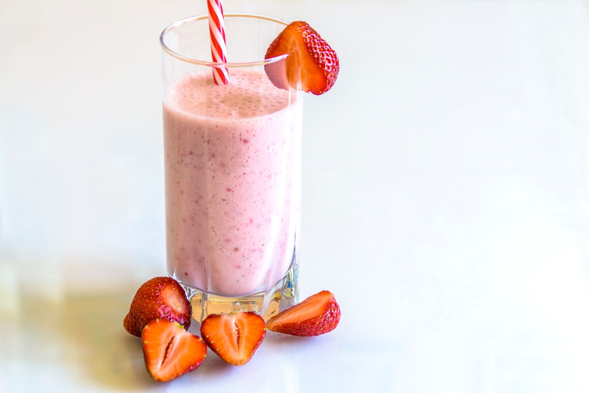 Pink strawberry protein smoothie in a glass with fresh strawberries
